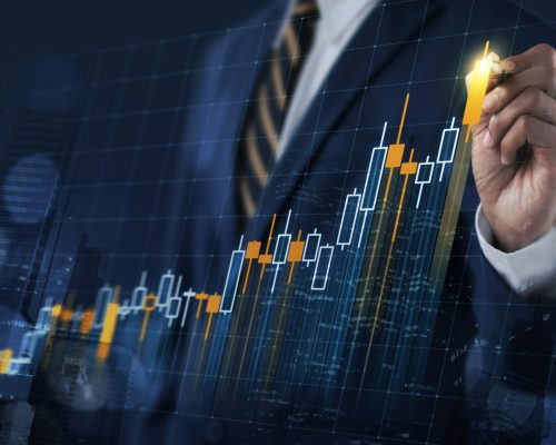 Business growth, progress or success concept. Businessman is drawing a growing virtual hologram stock bar chart on dark blue background.